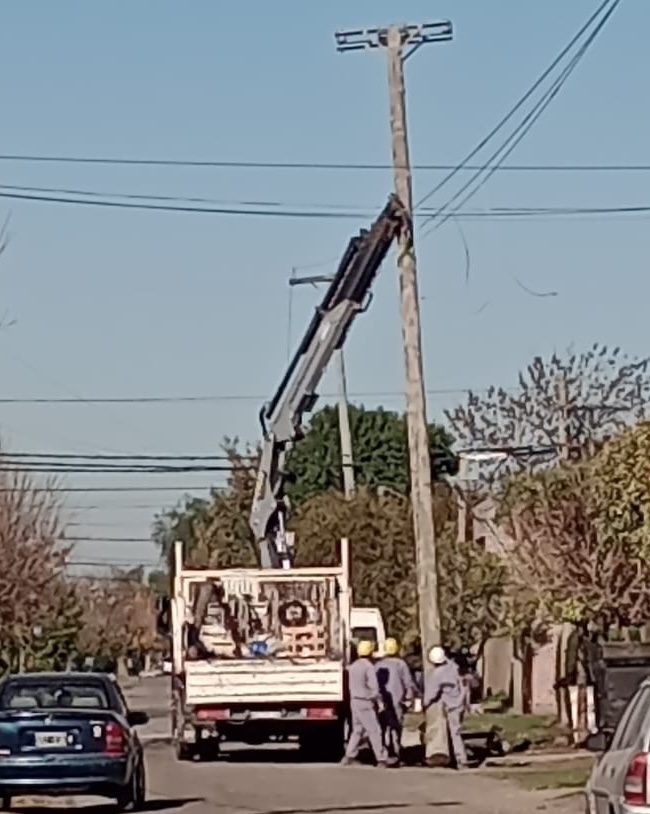 Cuadrilla instalando un poste eléctrico en una calle de barrio